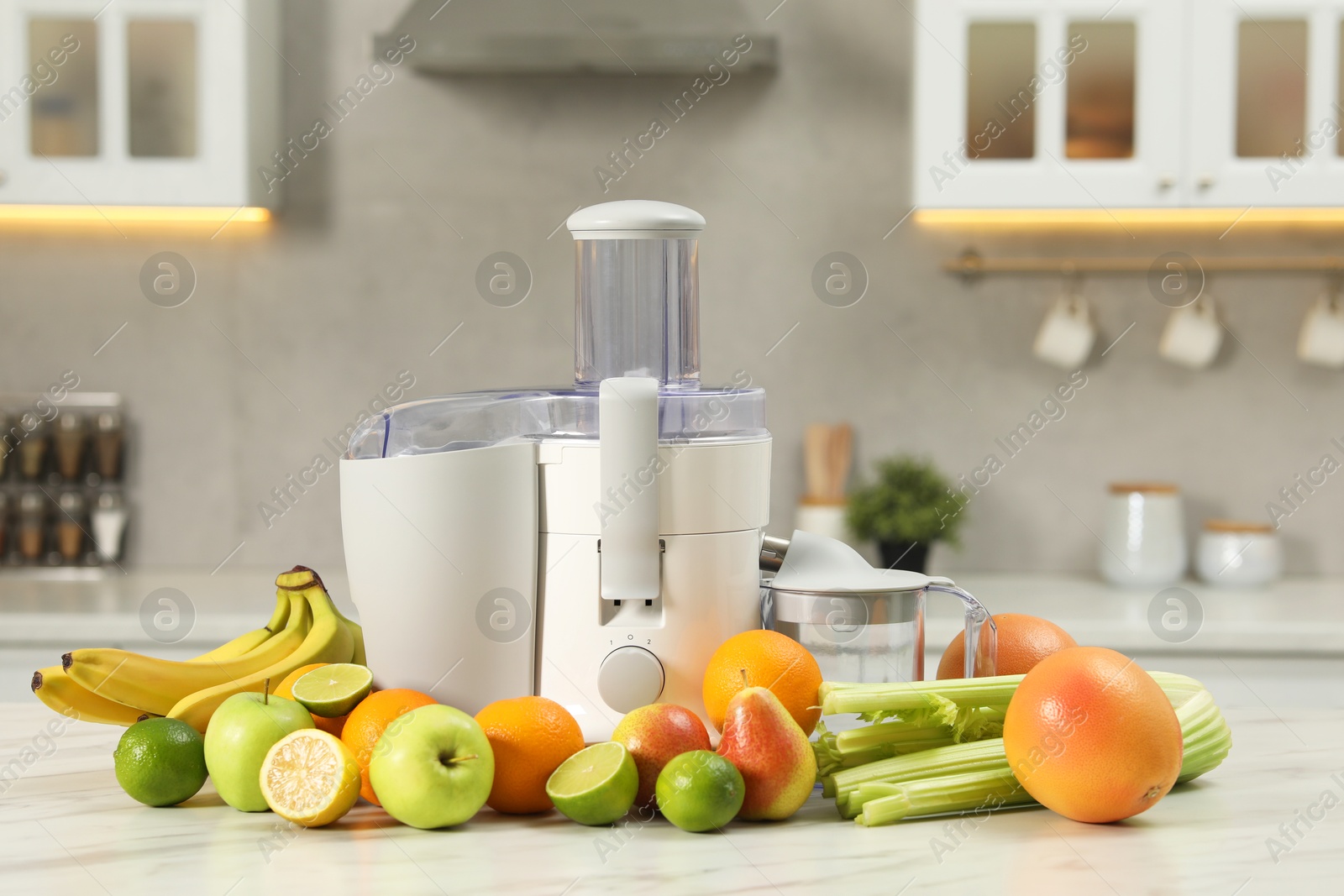 Photo of Modern juicer and fruits on white marble table in kitchen