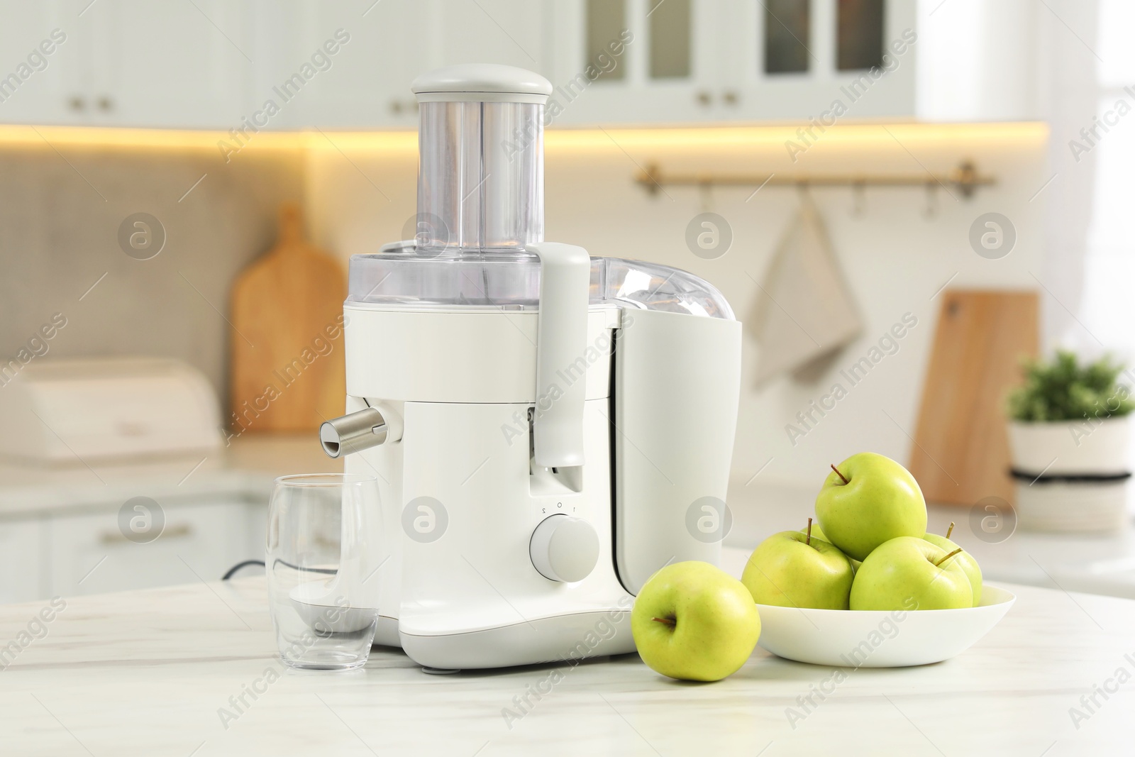 Photo of Modern juicer and apples on white marble table in kitchen