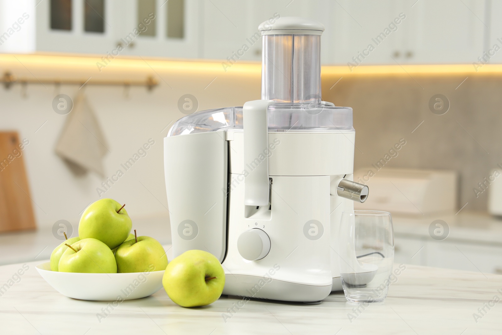 Photo of Modern juicer and apples on white marble table in kitchen