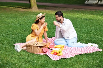 Photo of Lovely couple having picnic on green grass outdoors