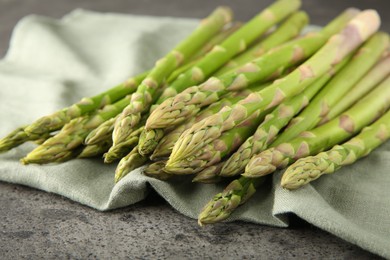 Photo of Fresh green asparagus stems on grey textured table, closeup