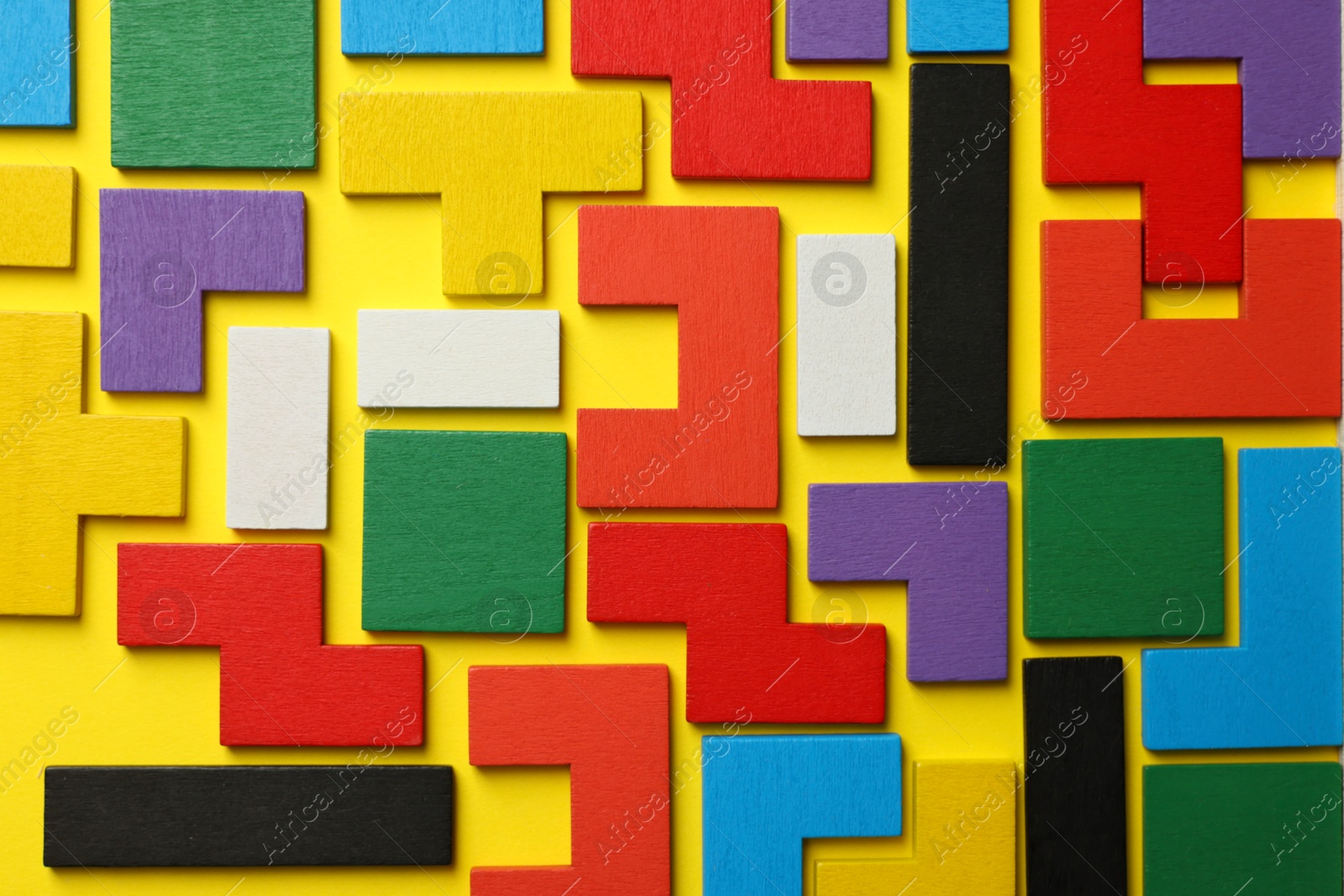 Photo of Colorful wooden puzzle pieces on yellow background, top view