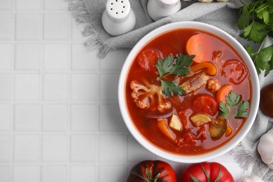 Photo of Delicious homemade stew in bowl on white tiled table, flat lay. Space for text