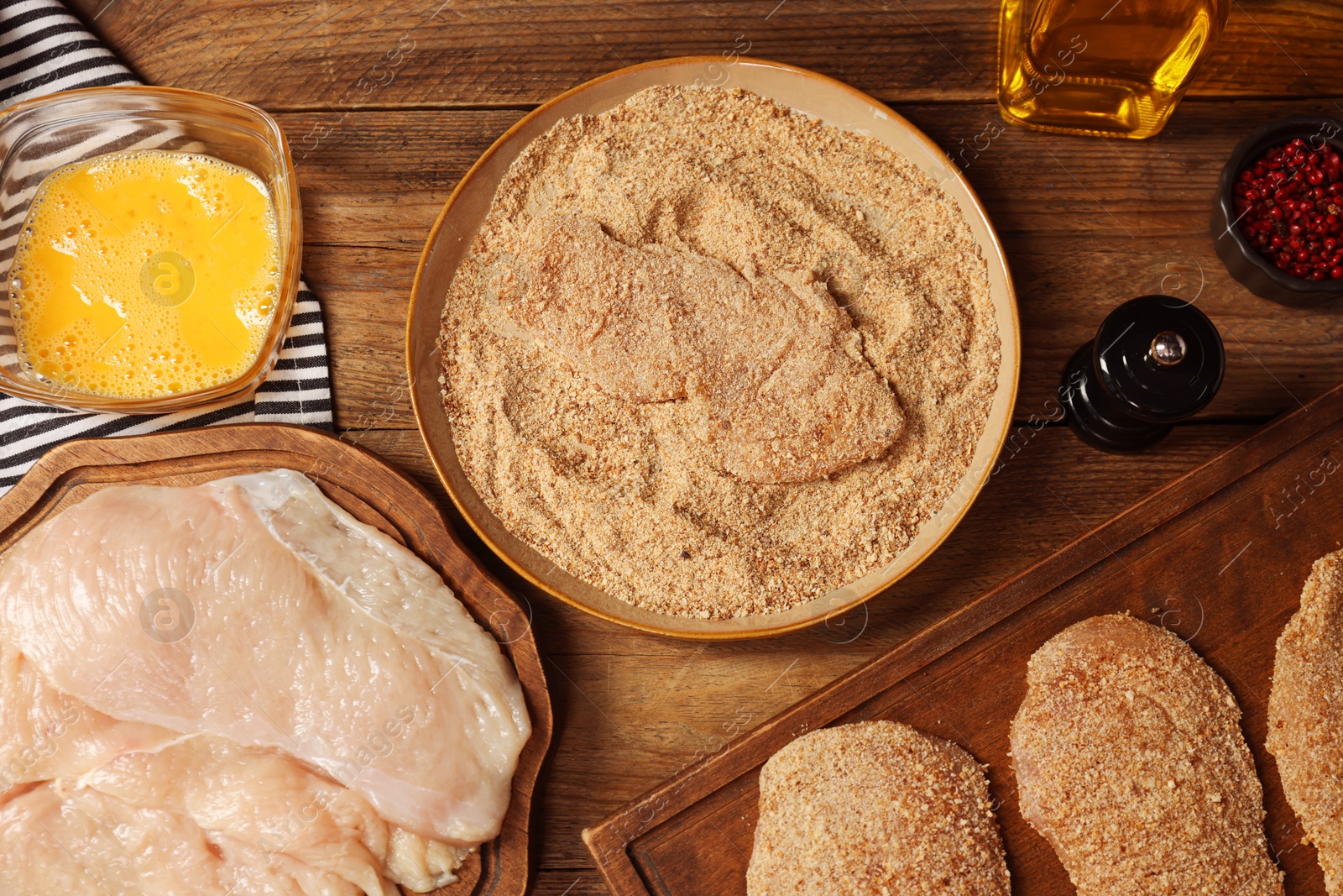 Photo of Making schnitzels. Raw meat and other ingredients on wooden table, flat lay