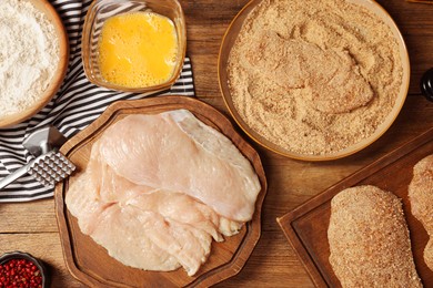 Making schnitzels. Raw meat and other ingredients on wooden table, flat lay