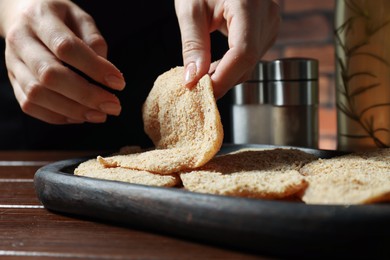 Photo of Woman making schnitzel at wooden table, closeup