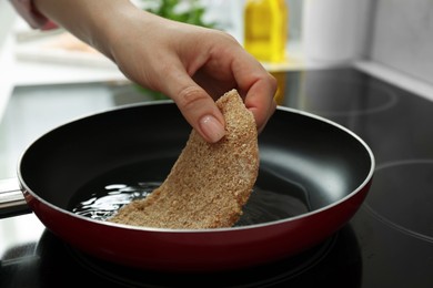 Woman cooking schnitzel in frying pan on stove, closeup