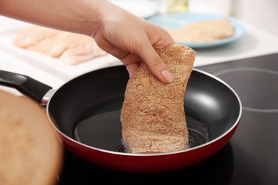 Woman cooking schnitzel in frying pan on stove, closeup