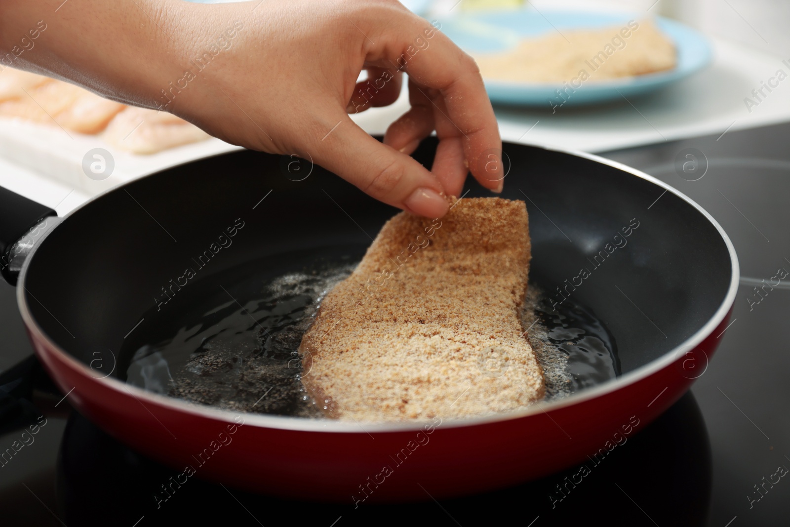 Photo of Woman cooking schnitzel in frying pan on stove, closeup