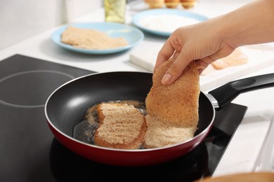 Woman cooking schnitzels in frying pan on stove, closeup