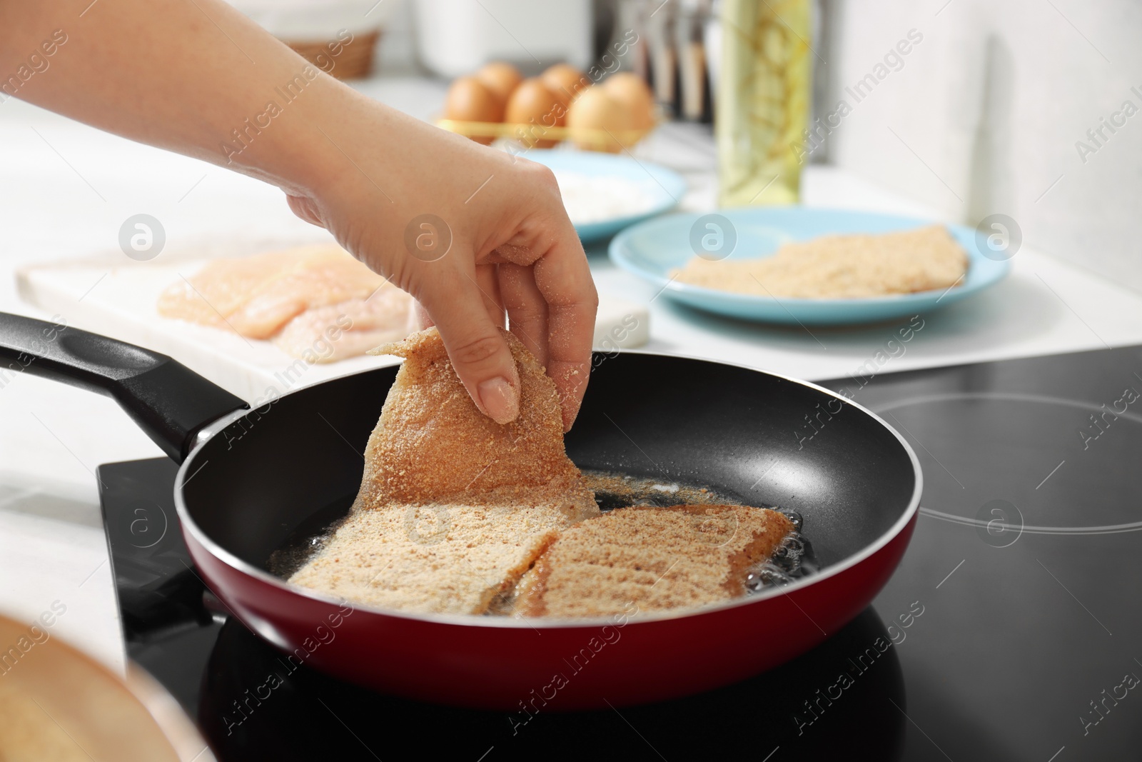 Photo of Woman cooking schnitzels in frying pan on stove, closeup