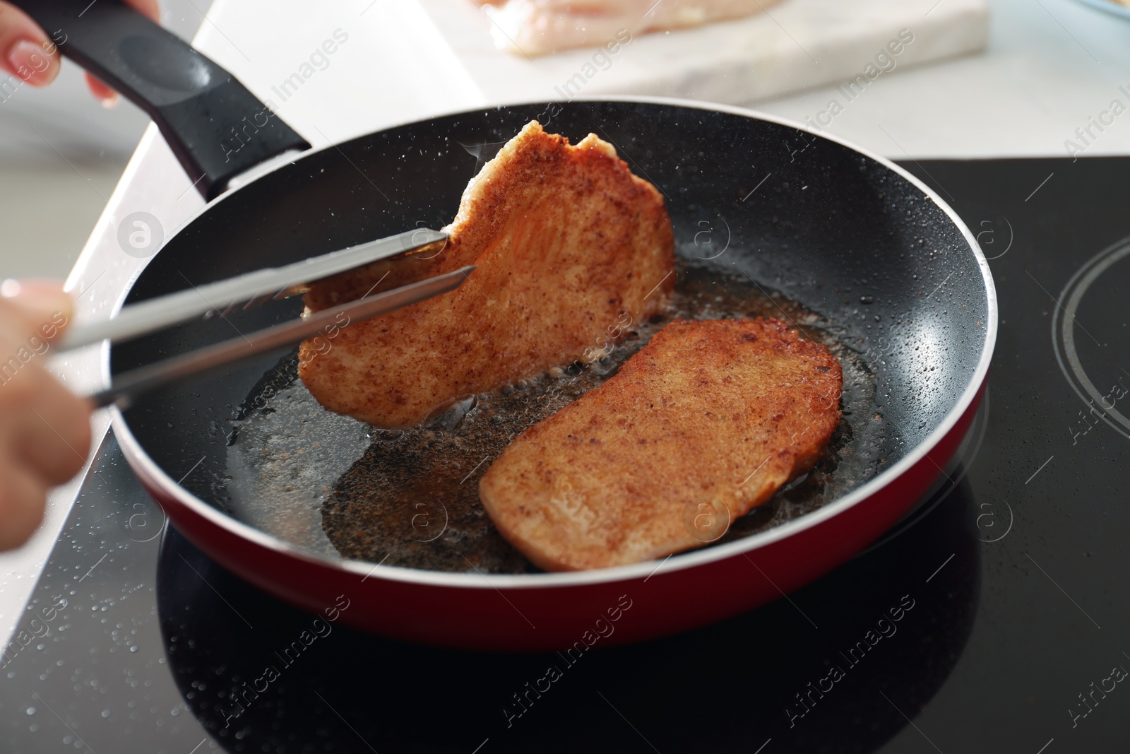 Photo of Woman cooking schnitzels in frying pan on stove, closeup