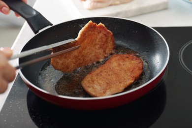 Woman cooking schnitzels in frying pan on stove, closeup