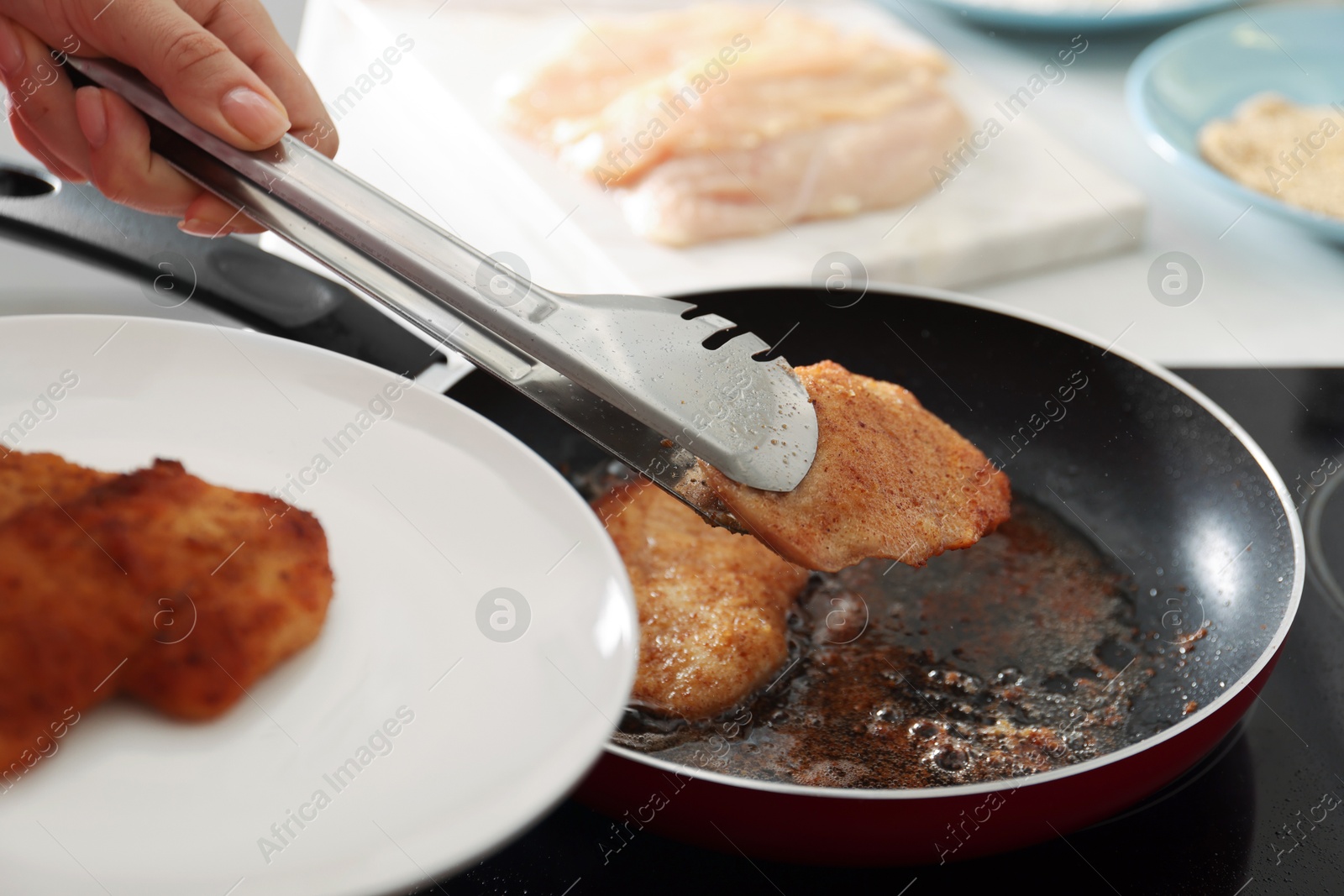 Photo of Woman cooking schnitzels in frying pan on stove, closeup