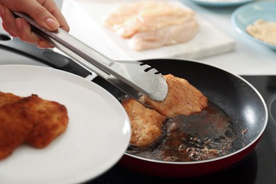 Woman cooking schnitzels in frying pan on stove, closeup