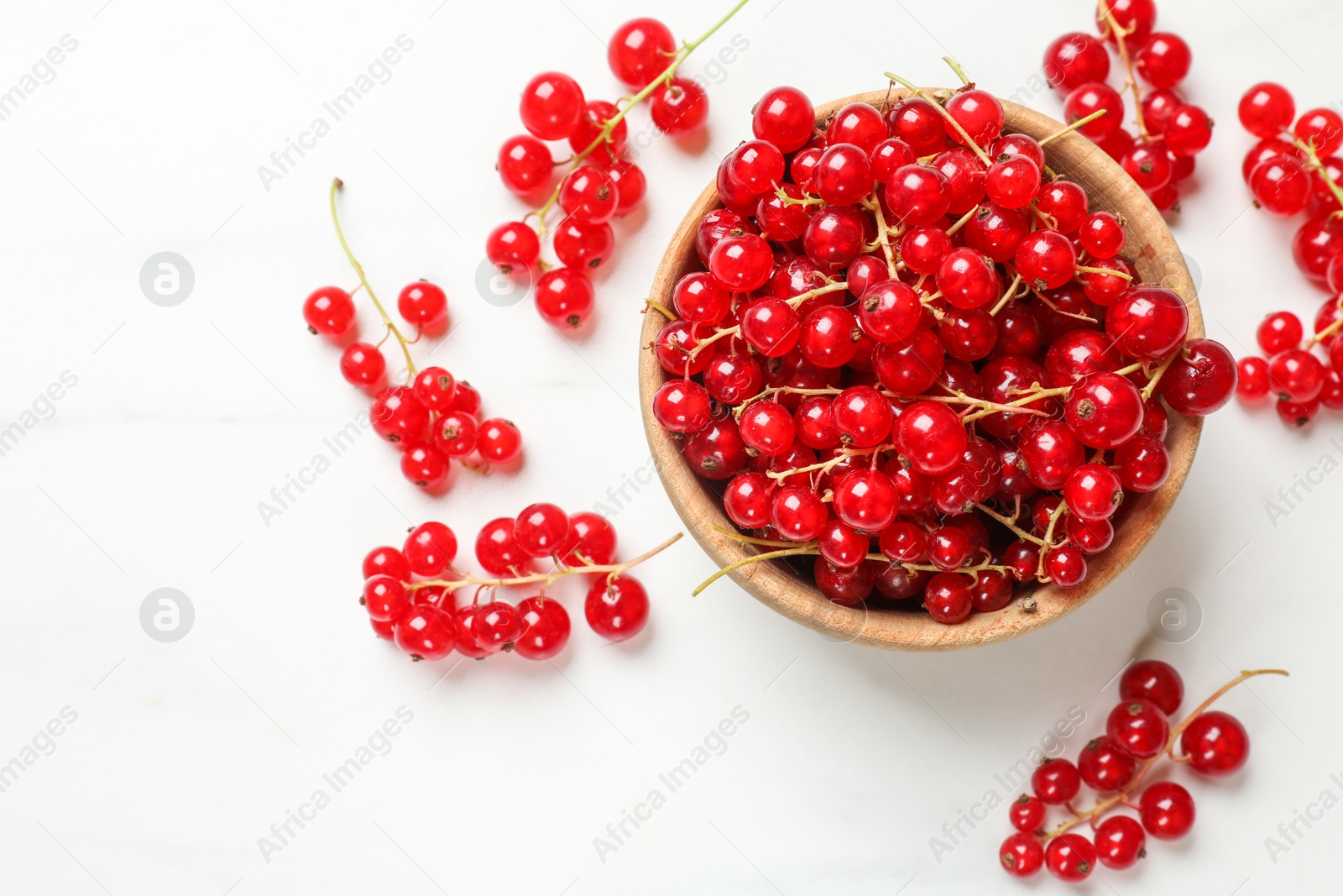 Photo of Fresh red currant berries in bowl on white table, top view