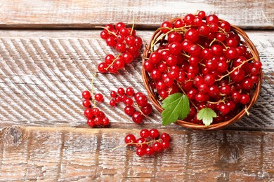 Photo of Fresh red currant berries in basket on wooden table, top view. Space for text