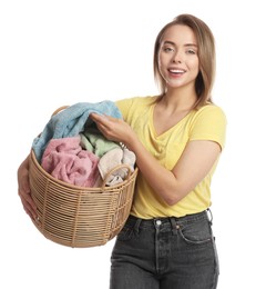 Happy young housewife with basket full of laundry on white background