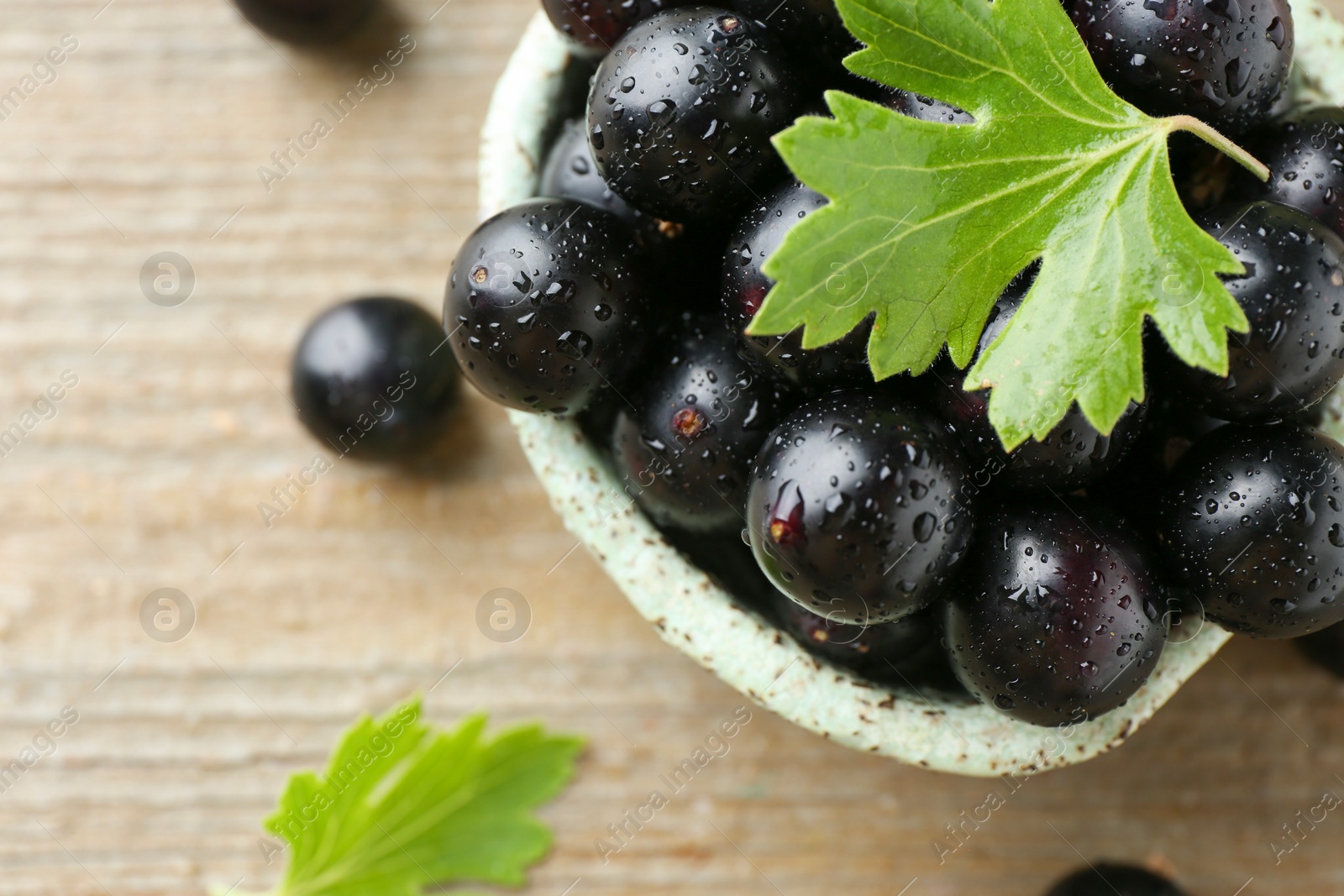 Photo of Fresh ripe black currant berries and leaves on wooden table, closeup