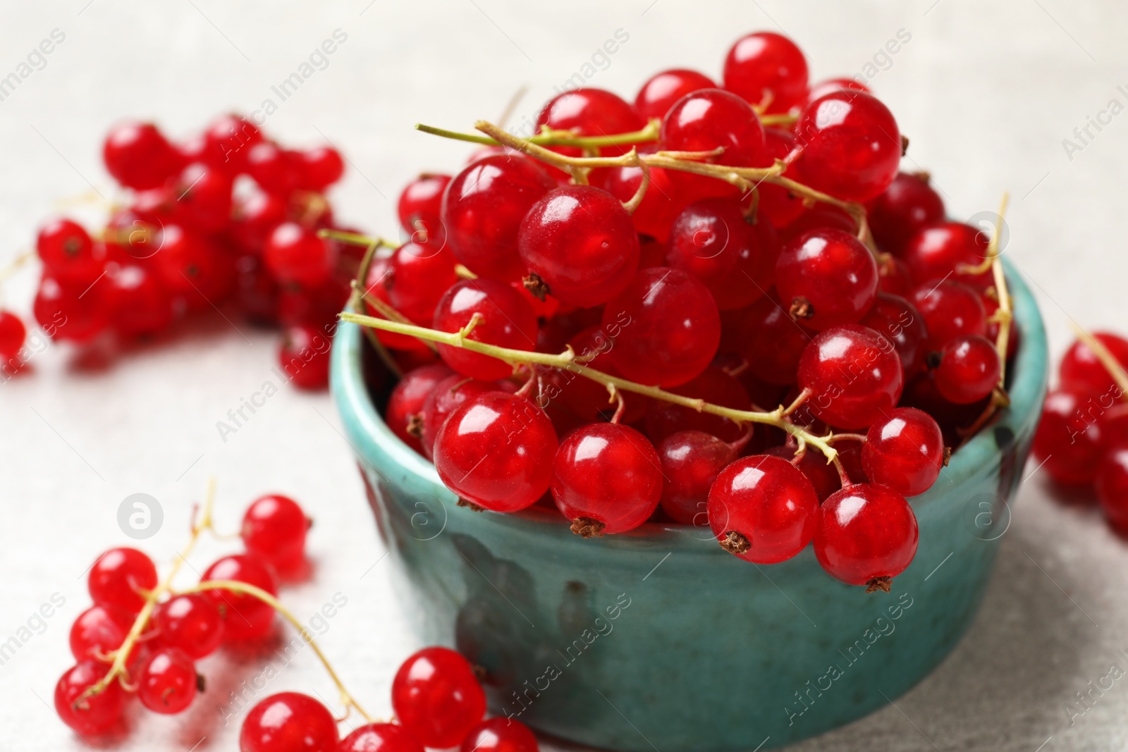 Photo of Fresh red currant in bowl on light table, closeup