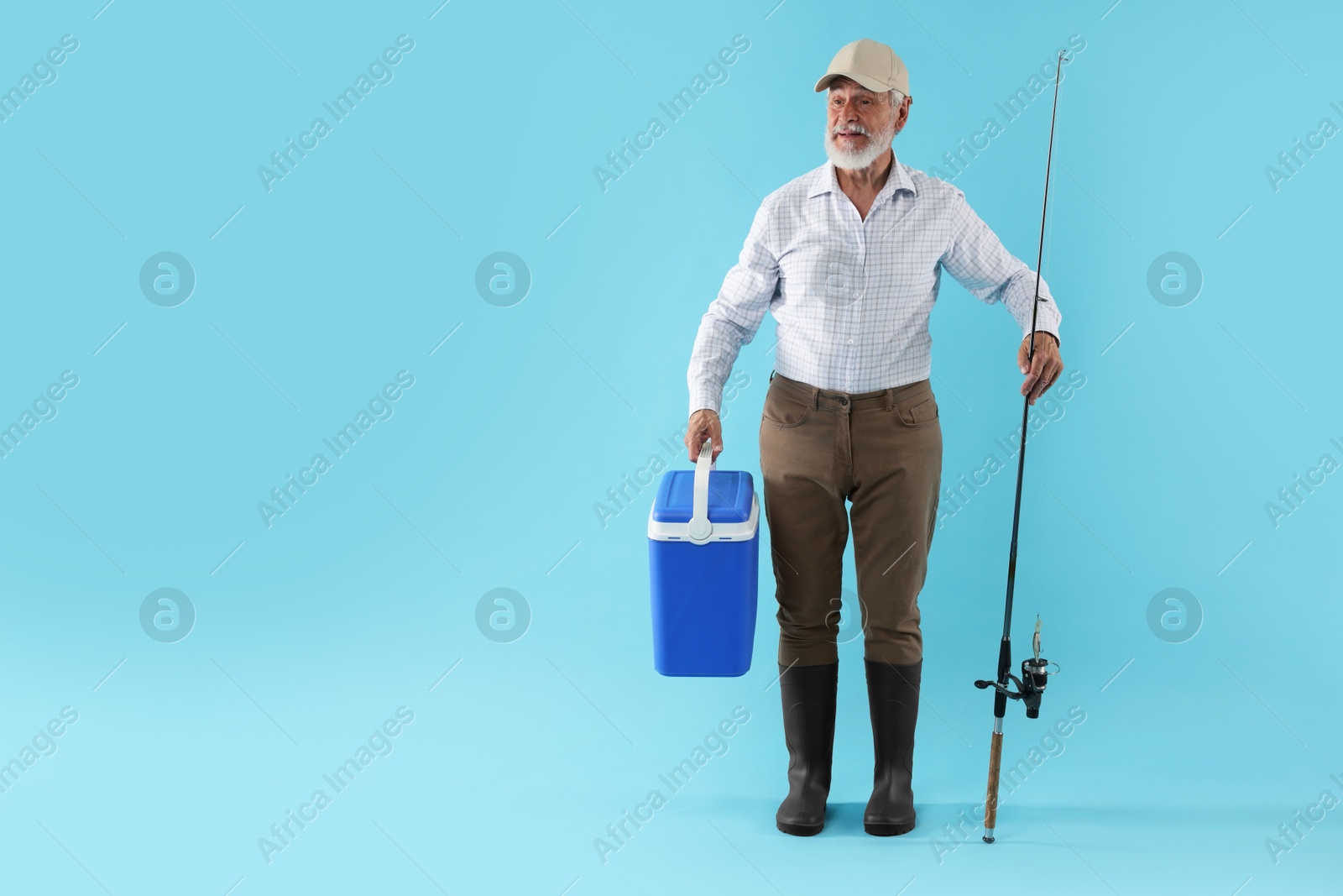 Photo of Fisherman with rod and cool box on light blue background