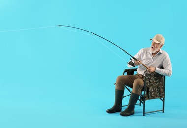 Photo of Fisherman with rod on fishing chair against light blue background