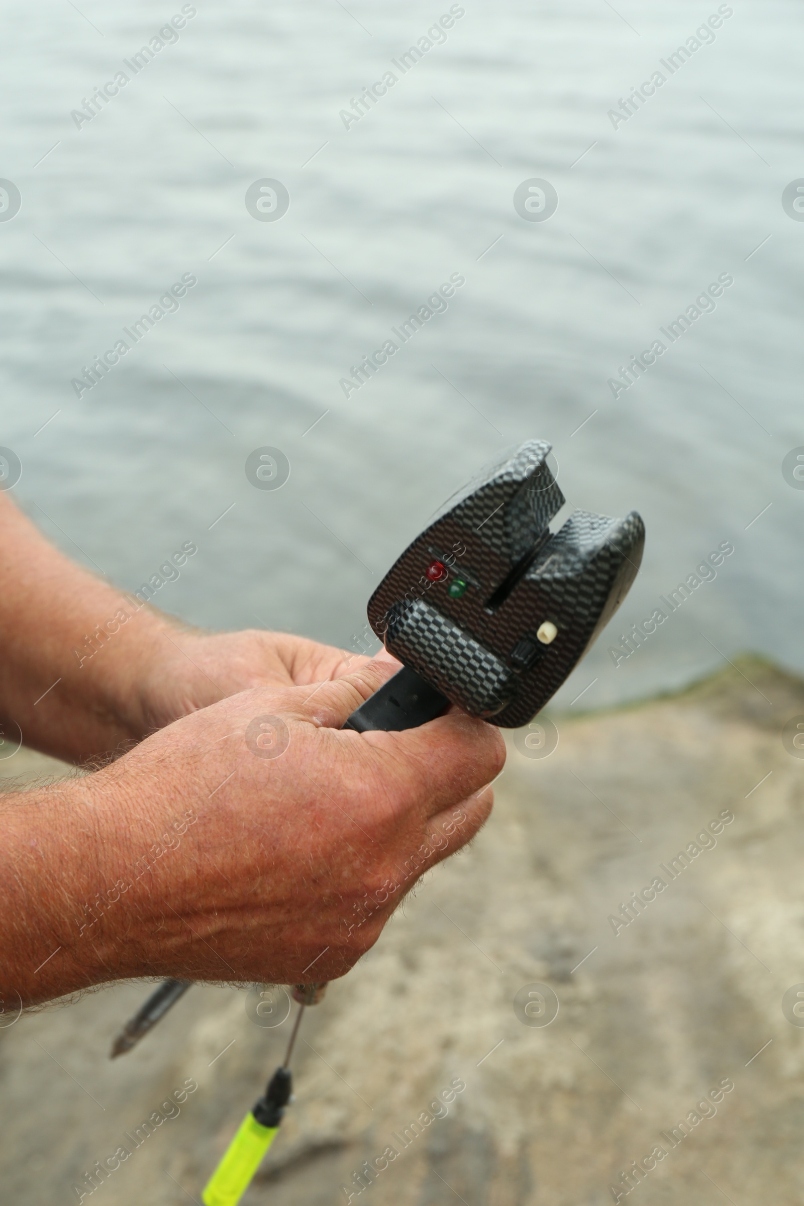 Photo of Senior fisherman holding fishing equipment outdoors, closeup