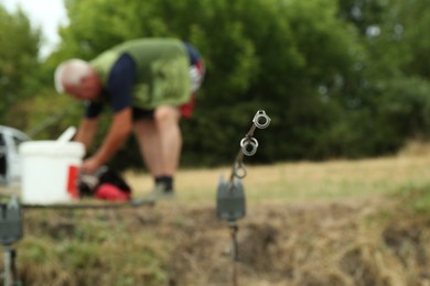 Photo of Senior man preparing baits outdoors, focus on fishing rod