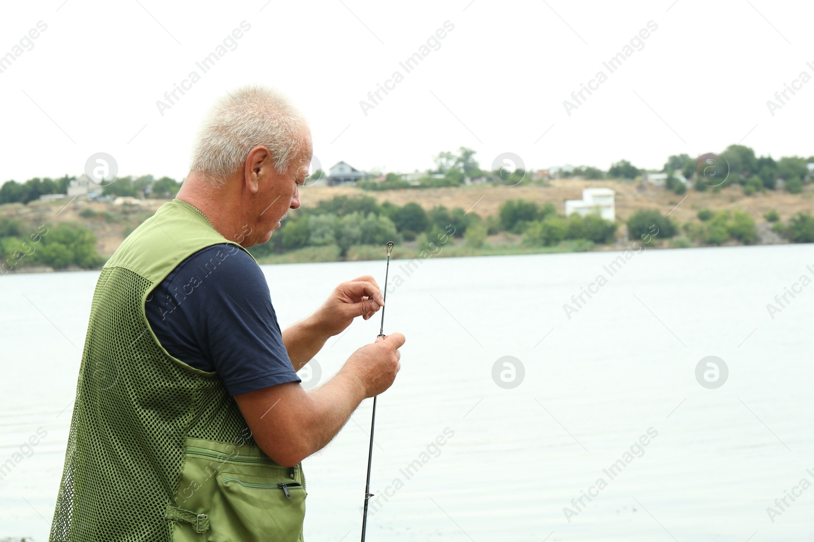 Photo of Fisherman with rod fishing near lake at summer