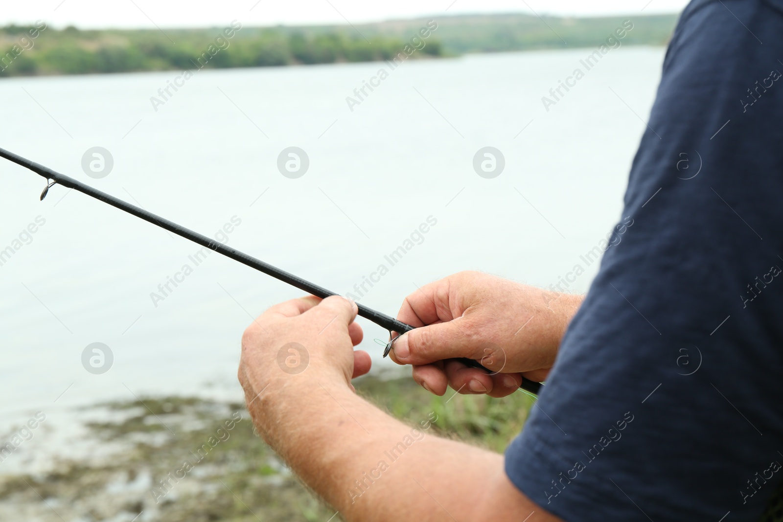 Photo of Fisherman with rod fishing near lake at summer, closeup