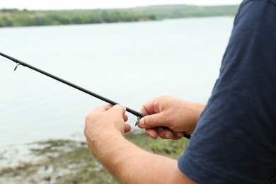 Fisherman with rod fishing near lake at summer, closeup