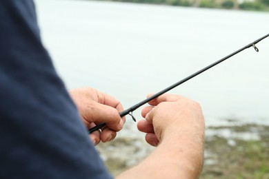 Fisherman with rod fishing near lake at summer, closeup