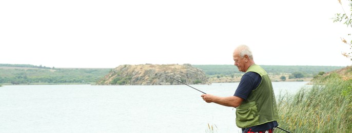 Fisherman with rod fishing near lake at summer