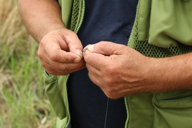 Senior fisherman holding fishing equipment outdoors, closeup