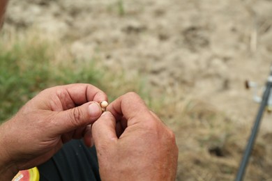 Senior fisherman holding fishing equipment outdoors, closeup. Space for text