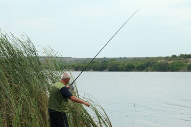 Photo of Fisherman with rod fishing near lake at summer