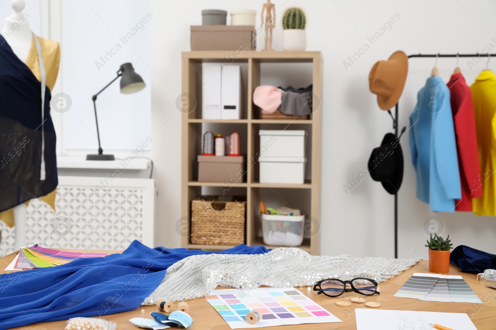 Photo of Different fashion designer`s supplies on wooden table in workshop