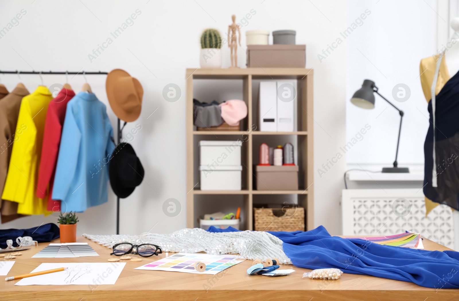 Photo of Different fashion designer`s supplies on wooden table in workshop