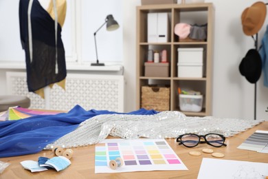 Photo of Different fashion designer`s supplies on wooden table in workshop