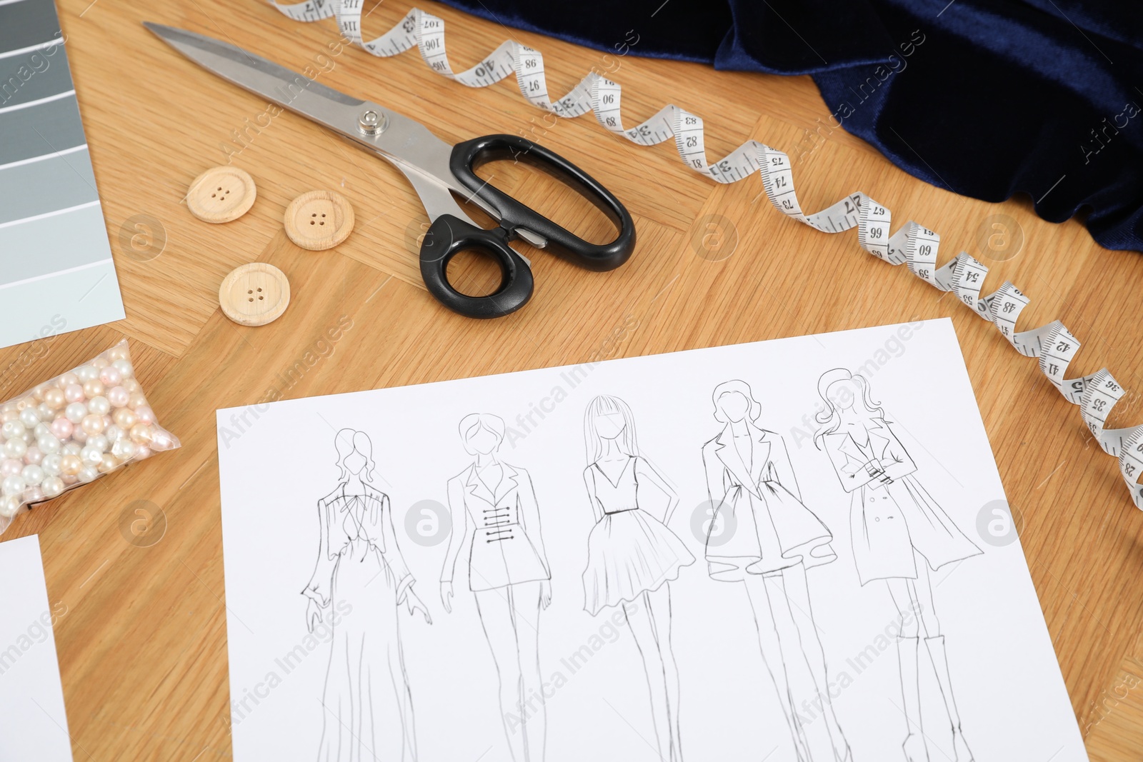 Photo of Sketch of stylish clothes and other fashion designer`s supplies on wooden table