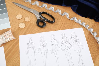 Photo of Sketch of stylish clothes and other fashion designer`s supplies on wooden table