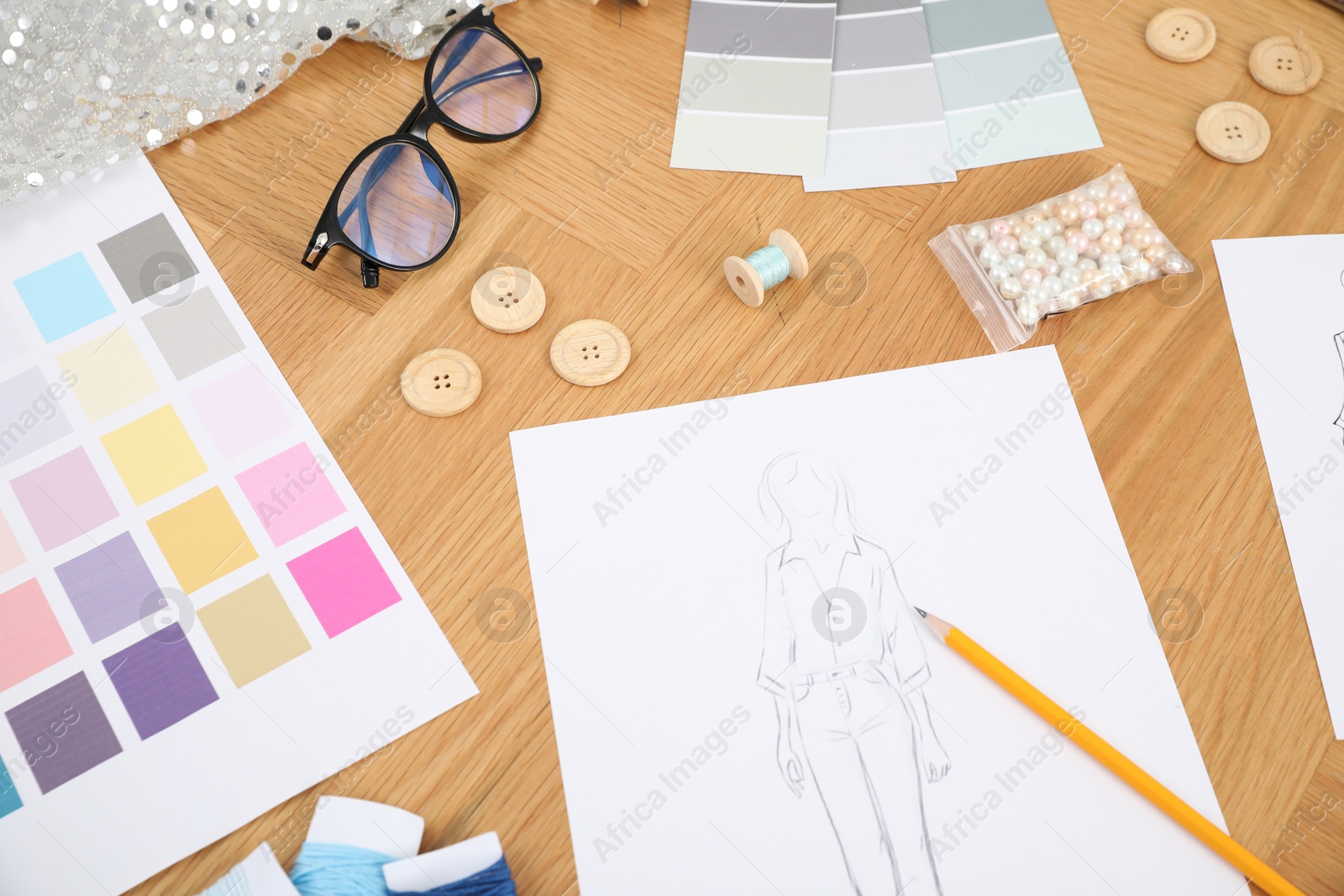 Photo of Sketch of stylish clothes, color palettes and other fashion designer`s supplies on wooden table