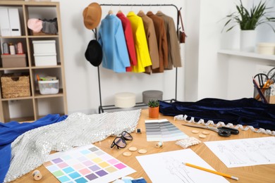 Photo of Different fashion designer`s supplies on wooden table in workshop