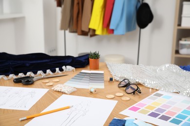 Photo of Different fashion designer`s supplies on wooden table in workshop