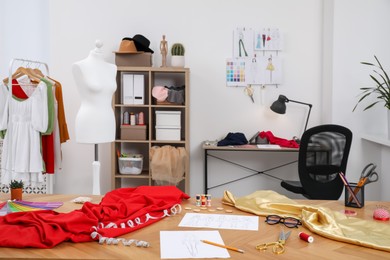 Photo of Fashion designer`s workplace with sketches of new outfits and other supplies