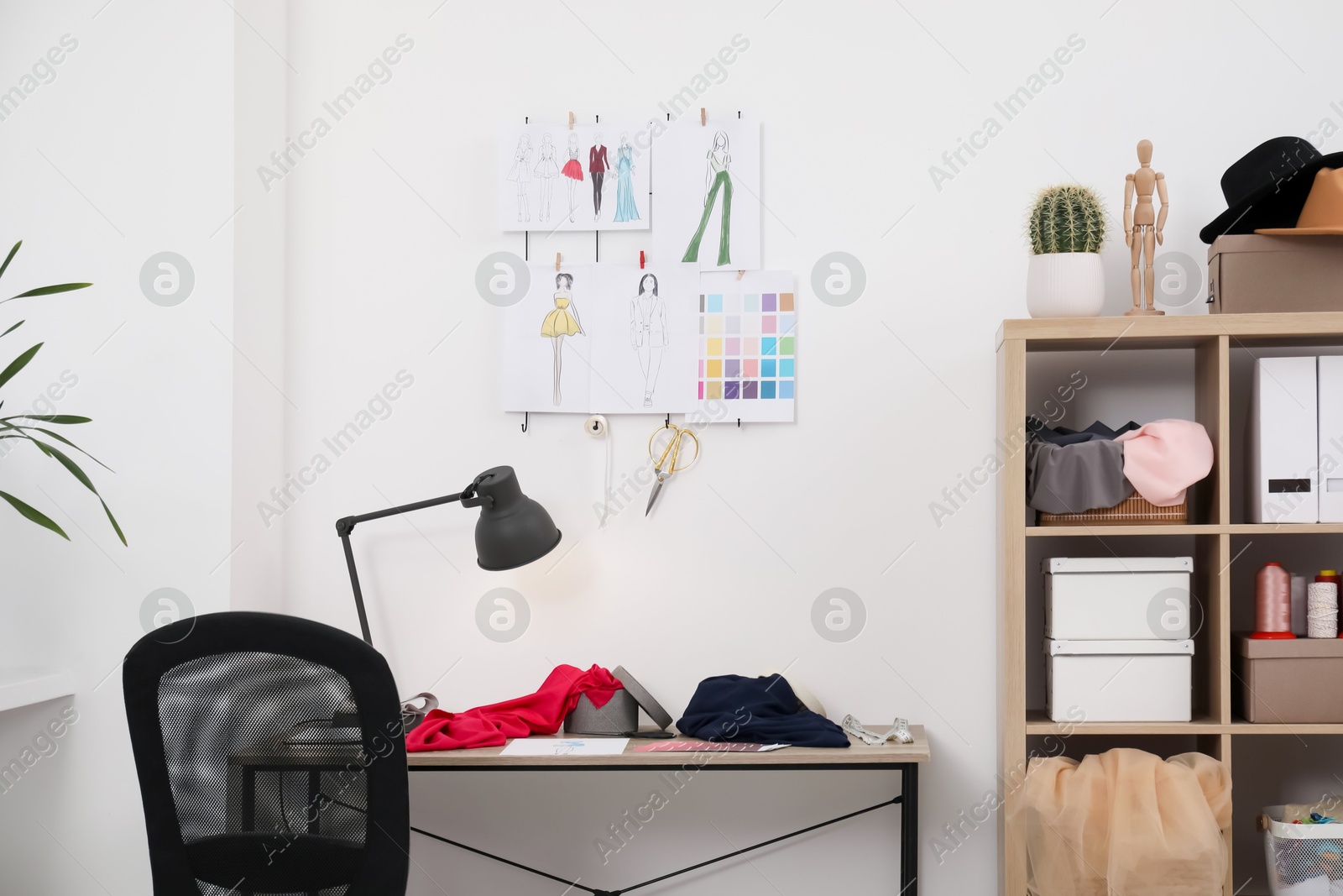 Photo of Fashion designer`s workplace with sketches of new outfits and other supplies