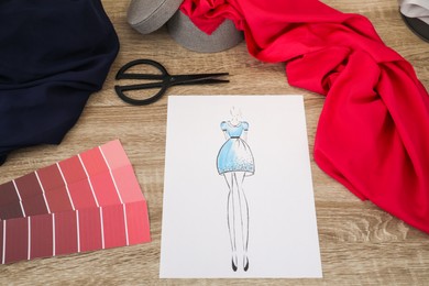 Photo of Sketch of stylish dress and other fashion designer`s supplies on wooden table, flat lay