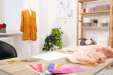 Photo of Different fashion designer`s supplies on wooden table in workshop