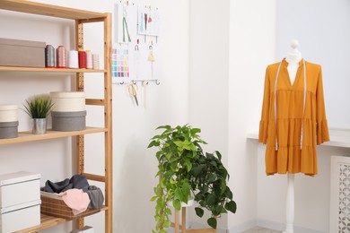 Photo of Fashion designer`s workplace with dress on mannequin and sketches of new outfits