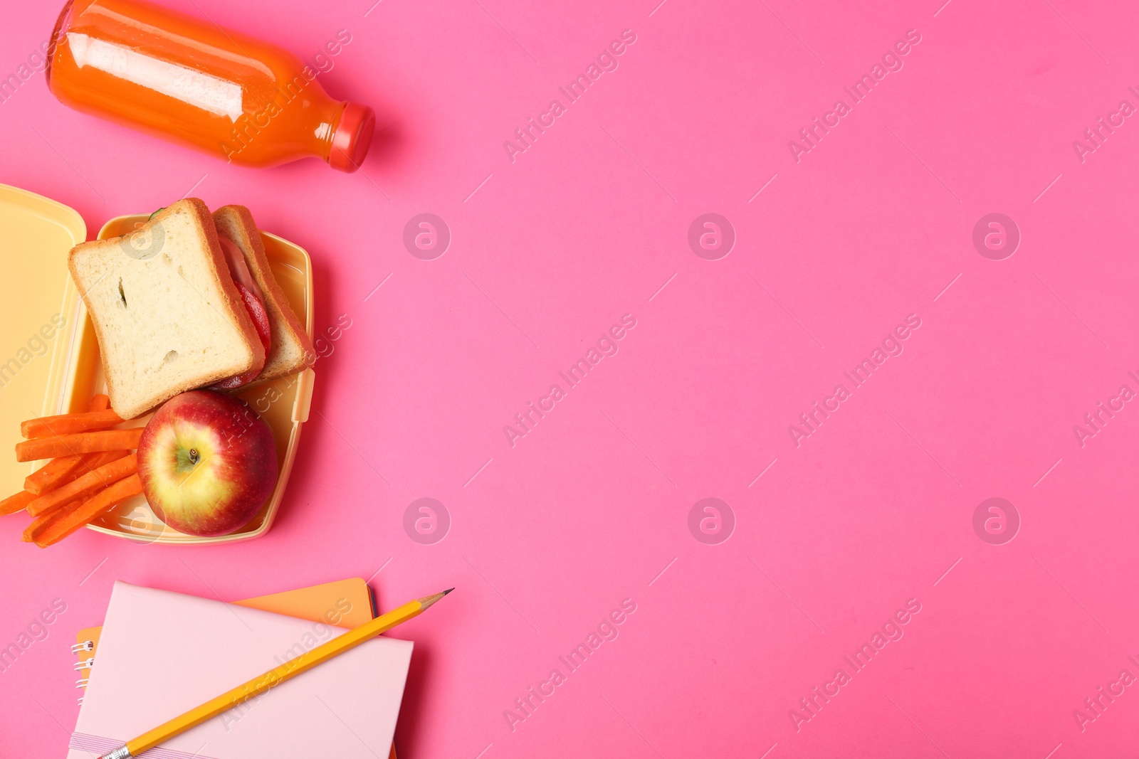 Photo of Lunch box with snacks, bottle of juice and stationery on pink background, flat lay. Space for text